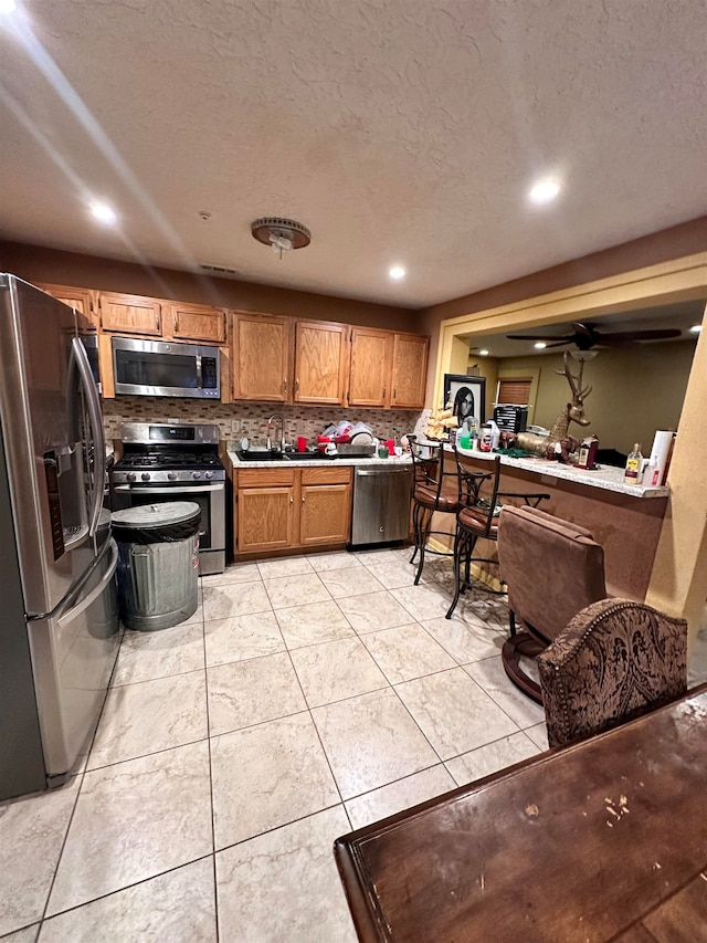 kitchen featuring light tile patterned floors, sink, backsplash, stainless steel appliances, and a textured ceiling