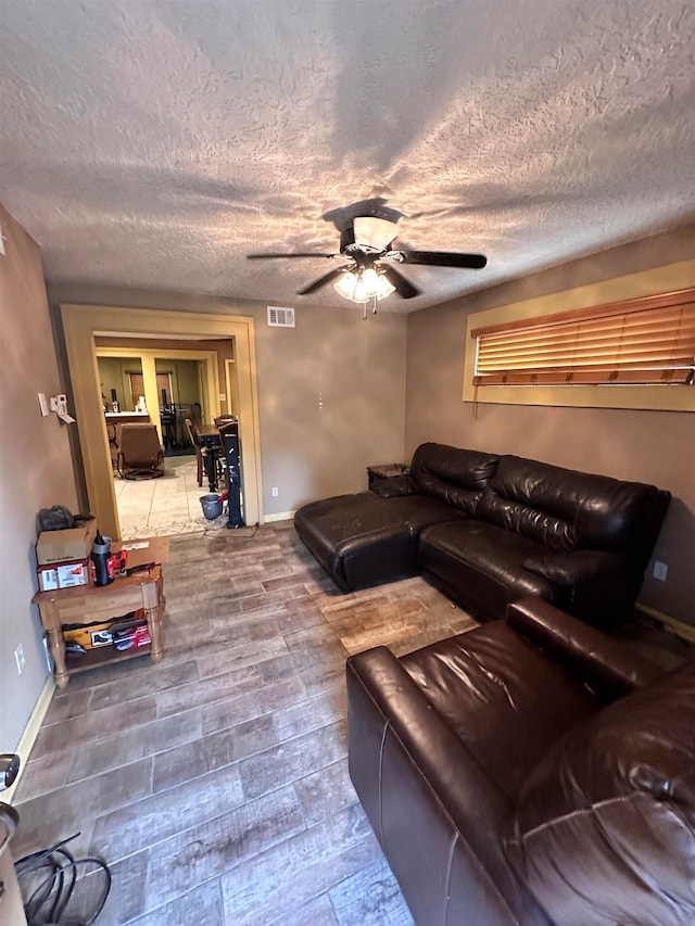 living room featuring hardwood / wood-style flooring, a textured ceiling, and ceiling fan