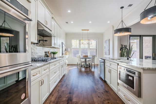 kitchen with a center island with sink, dark hardwood / wood-style flooring, white cabinetry, and appliances with stainless steel finishes