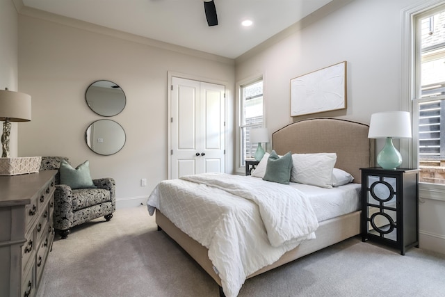 bedroom with light colored carpet, a closet, ornamental molding, and ceiling fan