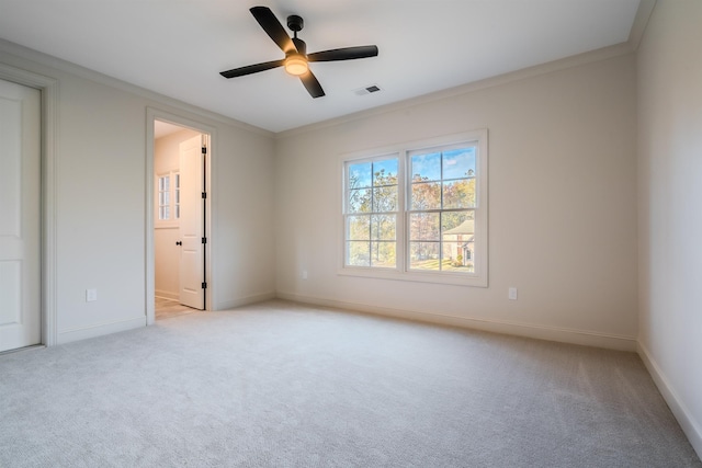 unfurnished bedroom featuring ceiling fan, light colored carpet, crown molding, and ensuite bath