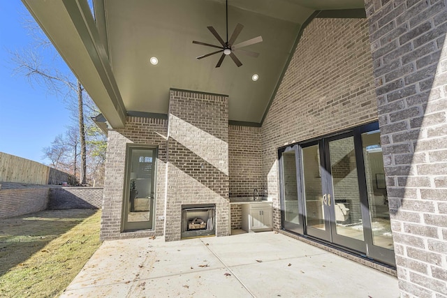 view of patio / terrace featuring french doors, an outdoor brick fireplace, ceiling fan, and sink