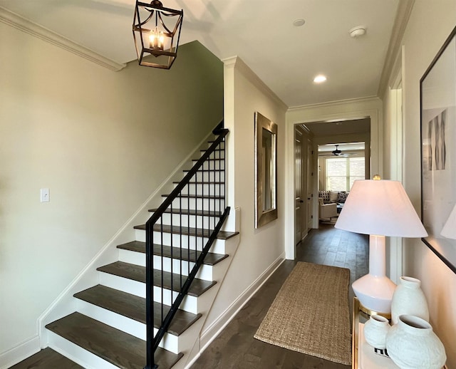 stairway featuring wood-type flooring, ceiling fan with notable chandelier, and ornamental molding