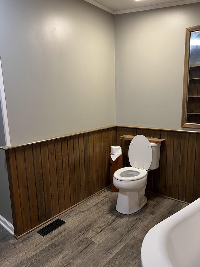 bathroom with hardwood / wood-style flooring, toilet, and ornamental molding