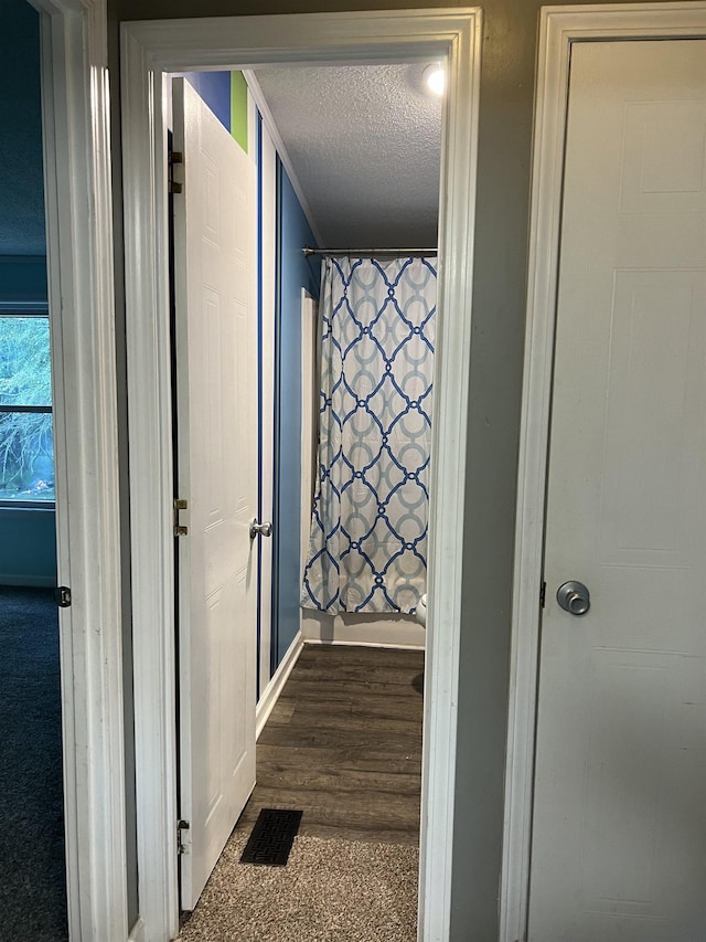 corridor featuring dark hardwood / wood-style flooring and a textured ceiling