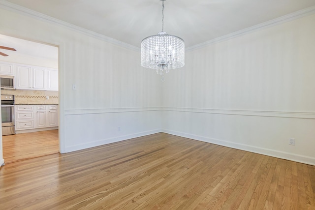 unfurnished dining area with ornamental molding, light wood-style floors, baseboards, and ceiling fan with notable chandelier