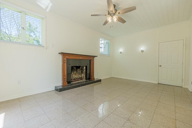 unfurnished living room featuring a ceiling fan, baseboards, a tiled fireplace, and ornamental molding