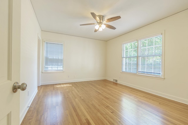 empty room with a ceiling fan, light wood-type flooring, visible vents, and baseboards