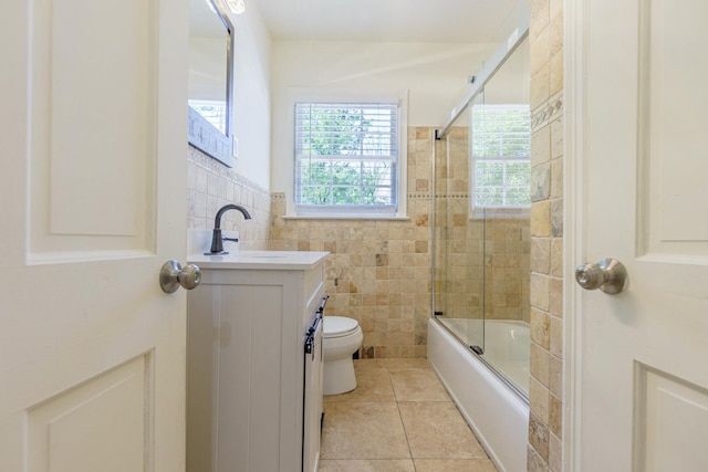 full bathroom featuring shower / bath combination with glass door, tile walls, toilet, vanity, and tile patterned flooring