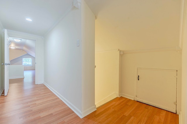 hallway with crown molding, baseboards, lofted ceiling, and light wood-style floors