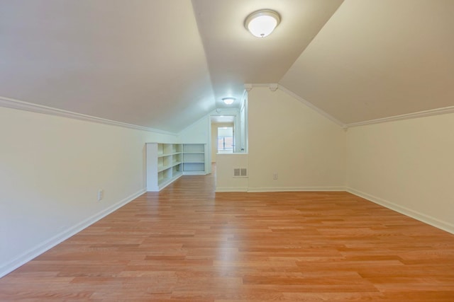 bonus room featuring built in shelves, lofted ceiling, visible vents, light wood-style floors, and baseboards