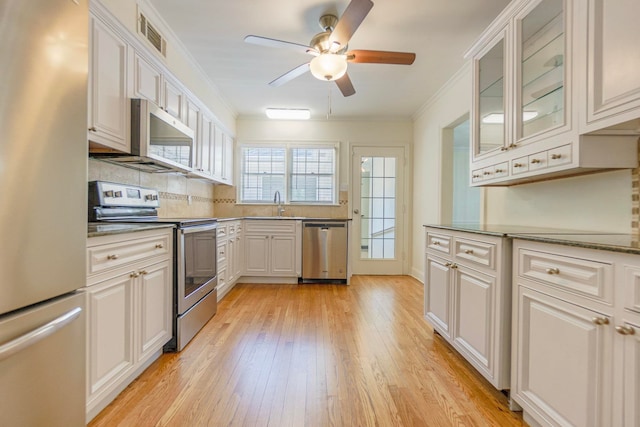 kitchen with appliances with stainless steel finishes, white cabinetry, and glass insert cabinets