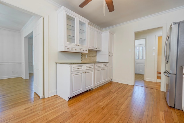 kitchen featuring glass insert cabinets, white cabinetry, crown molding, and freestanding refrigerator