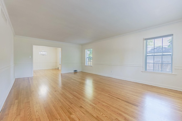 spare room featuring a chandelier, crown molding, plenty of natural light, and light wood-style flooring