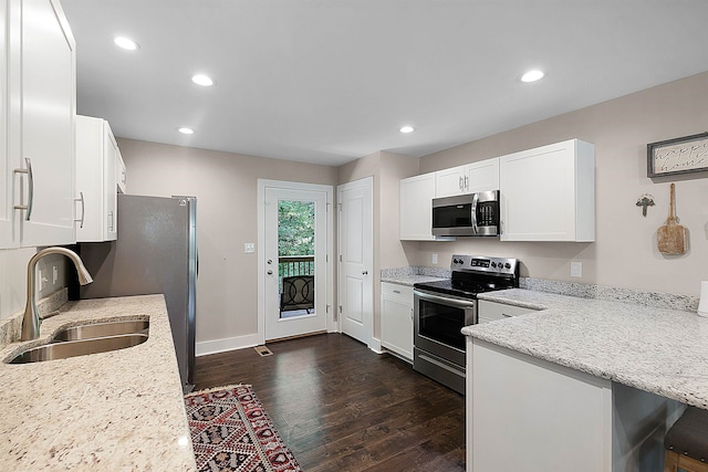 kitchen featuring dark hardwood / wood-style floors, white cabinets, stainless steel appliances, a breakfast bar, and kitchen peninsula