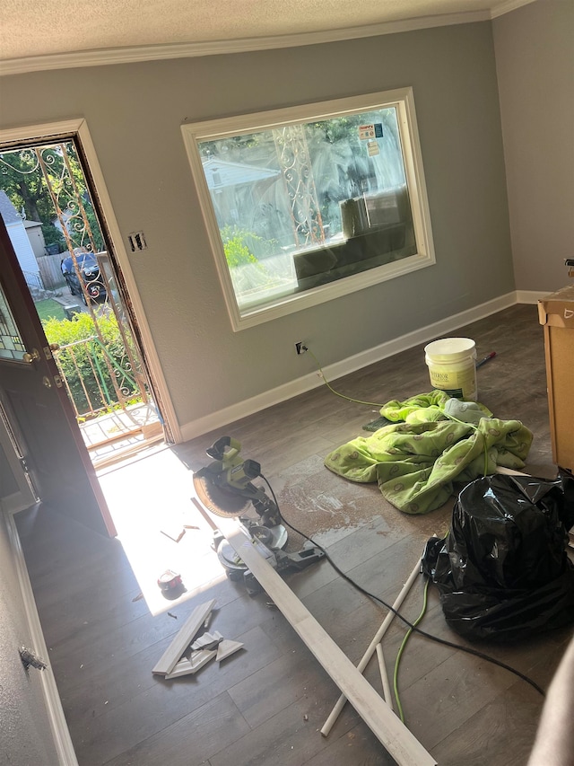 empty room with a textured ceiling, hardwood / wood-style floors, and crown molding