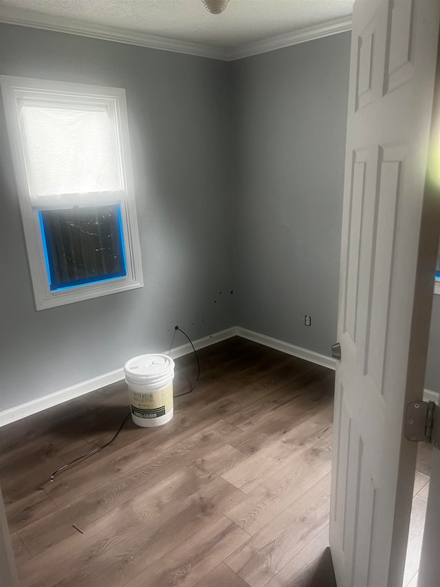 unfurnished room featuring a textured ceiling, light hardwood / wood-style floors, and ornamental molding