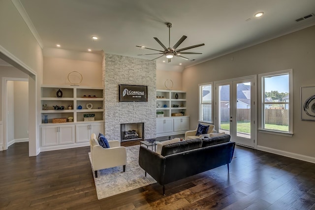 living room with crown molding, dark hardwood / wood-style floors, a fireplace, built in shelves, and french doors