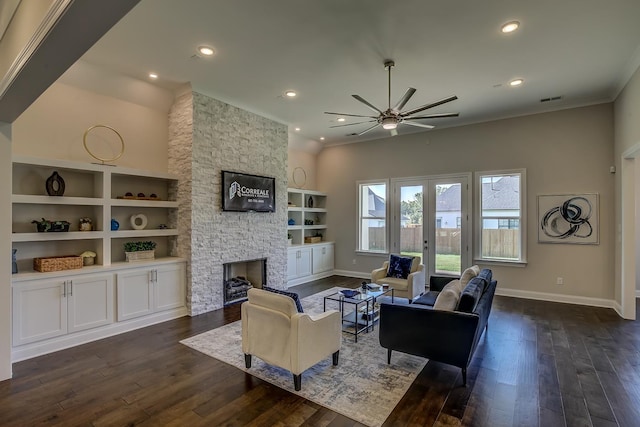 living room featuring french doors, built in shelves, dark hardwood / wood-style flooring, ceiling fan, and a fireplace