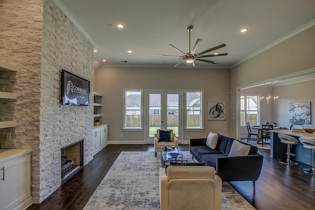 living room with ornamental molding, dark hardwood / wood-style flooring, a stone fireplace, and a wealth of natural light