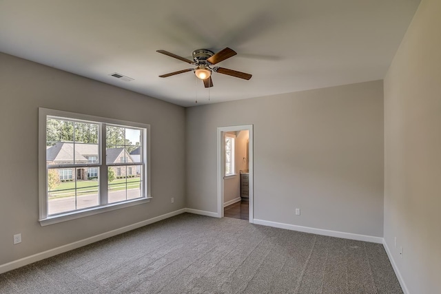 spare room with ceiling fan and dark carpet