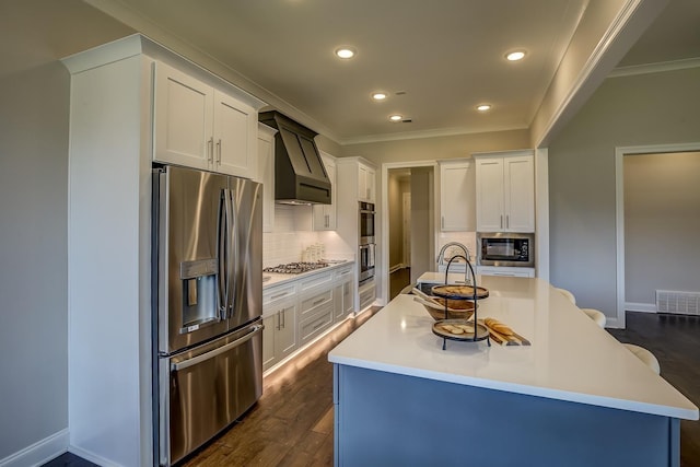 kitchen featuring premium range hood, white cabinetry, stainless steel appliances, and a center island with sink