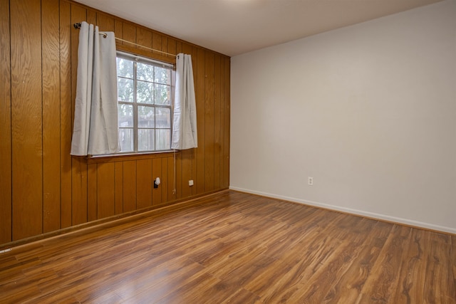 unfurnished room featuring wood walls and dark hardwood / wood-style floors