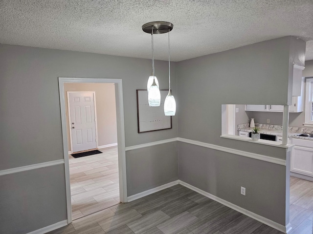 unfurnished dining area featuring a textured ceiling