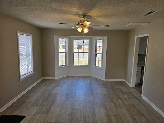 unfurnished room featuring a textured ceiling, ceiling fan, and a wealth of natural light