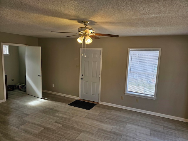 tiled spare room with a textured ceiling and ceiling fan