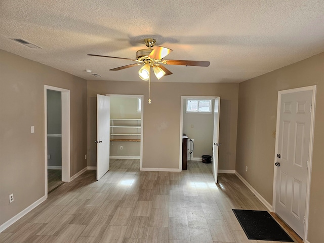 unfurnished bedroom with a closet, a walk in closet, a textured ceiling, and ceiling fan