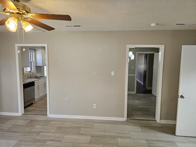 empty room featuring ceiling fan, sink, light tile flooring, and a textured ceiling