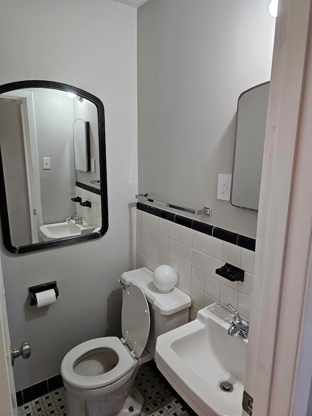 bathroom with tile flooring, tasteful backsplash, toilet, and sink