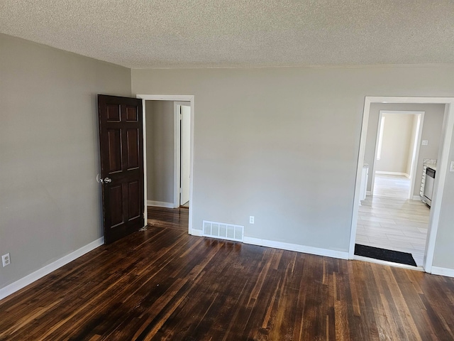 unfurnished room featuring a textured ceiling and dark hardwood / wood-style flooring