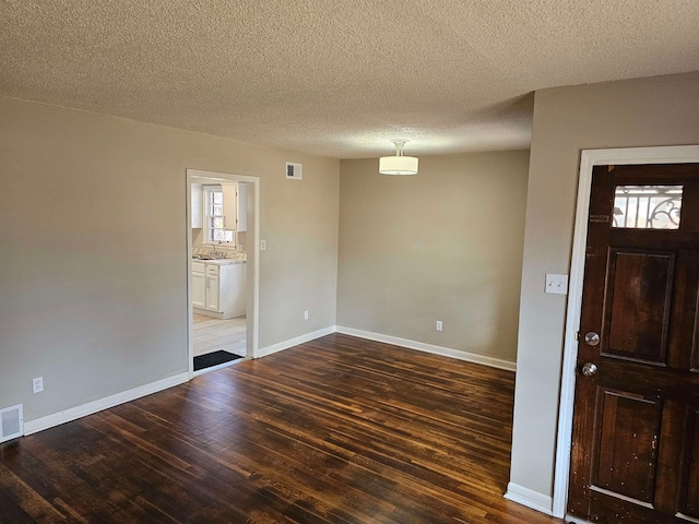 spare room with dark hardwood / wood-style flooring, a textured ceiling, and sink