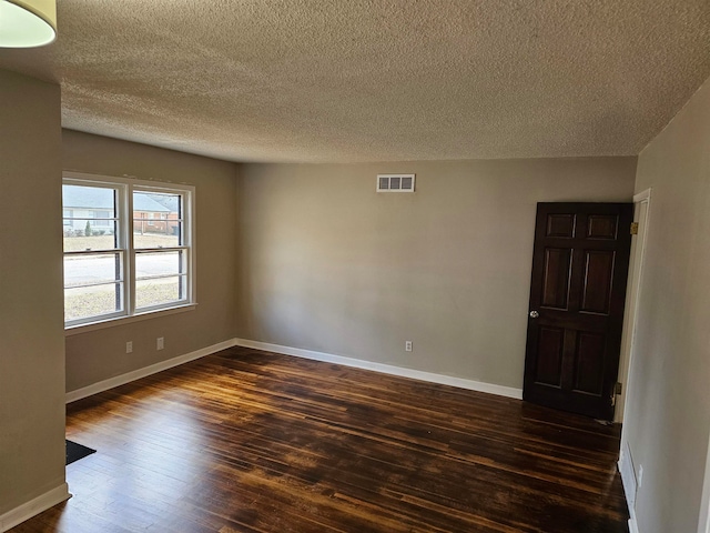 empty room featuring dark hardwood / wood-style floors and a textured ceiling