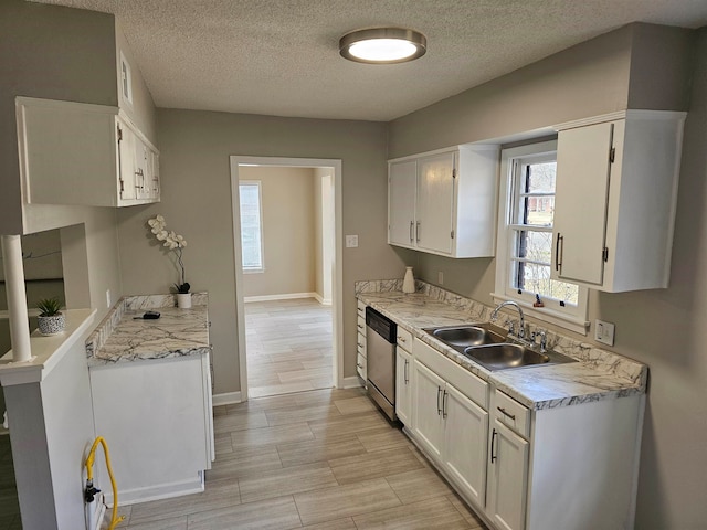 kitchen featuring a textured ceiling, white cabinetry, sink, dishwasher, and light stone counters