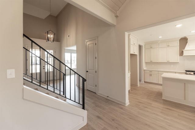 stairs featuring hardwood / wood-style flooring, ornamental molding, a chandelier, and high vaulted ceiling