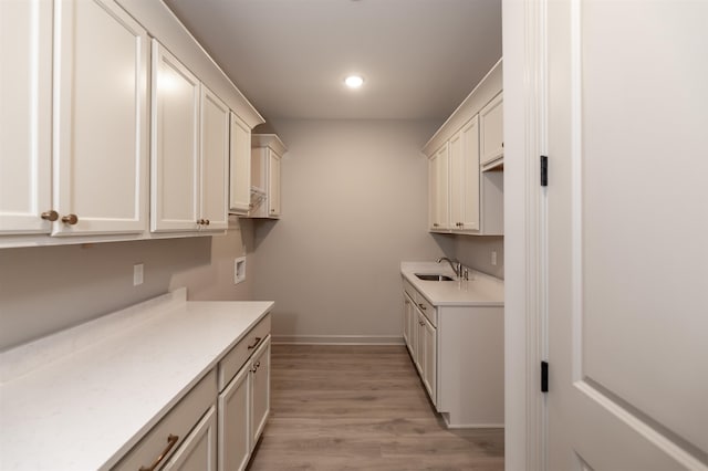 kitchen with white cabinets, sink, and light wood-type flooring