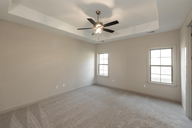 carpeted empty room featuring a tray ceiling and ceiling fan