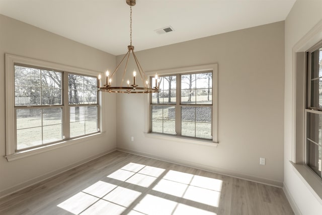 unfurnished dining area featuring an inviting chandelier and light wood-type flooring