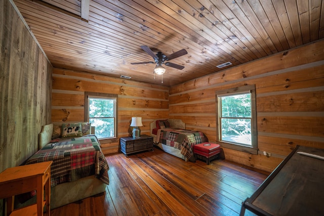 bedroom featuring multiple windows, dark wood-type flooring, wood ceiling, and wooden walls