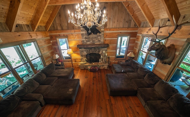 living room with dark hardwood / wood-style flooring, an inviting chandelier, wood walls, beamed ceiling, and a stone fireplace