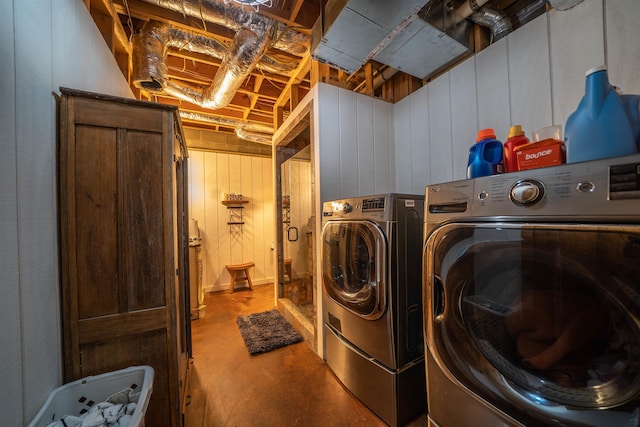 washroom with washer and dryer and wood walls