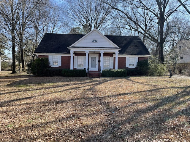 greek revival house featuring a porch and a front lawn