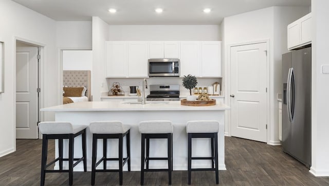 kitchen featuring appliances with stainless steel finishes, white cabinetry, an island with sink, and dark wood-type flooring