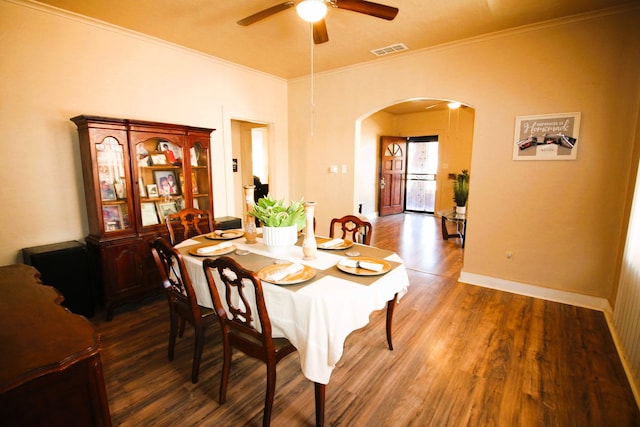 dining space featuring ceiling fan, ornamental molding, and dark wood-type flooring