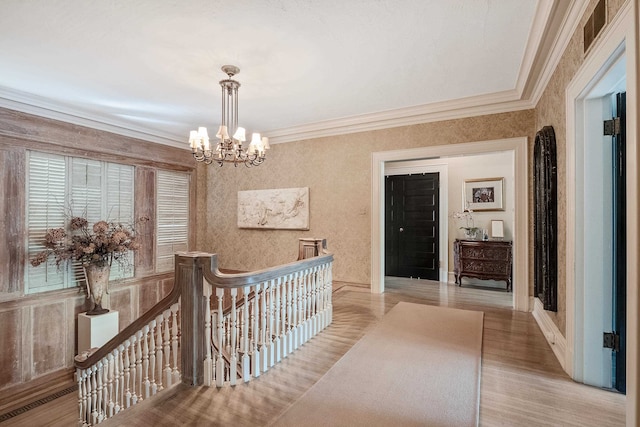 corridor featuring crown molding, a notable chandelier, and light wood-type flooring