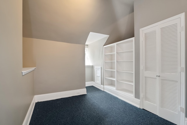 additional living space featuring lofted ceiling and dark carpet