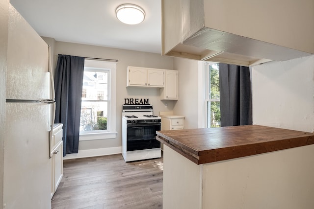 kitchen featuring white appliances, white cabinetry, a healthy amount of sunlight, and light hardwood / wood-style flooring